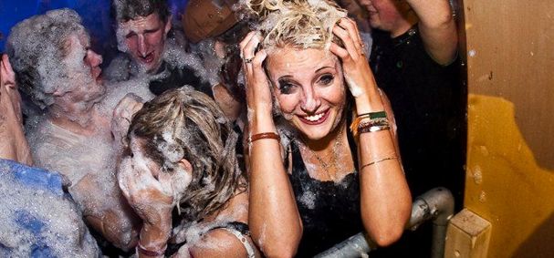 smiling girl at a foam party rubbing foam in her hair